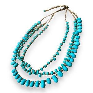 3 strand brass and teal beaded necklace with dangle clasp.